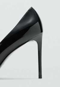 Stiletto in vernice nera con punta affusolata, caratterizzato da una finitura liscia e lucida e un design elegante con tacco alto e sottile.