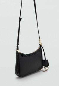 Sort læder crossbody taske med en buet form, guld lynlås og hardware detaljer. Har en aftagelig nøglering og justerbar rem.