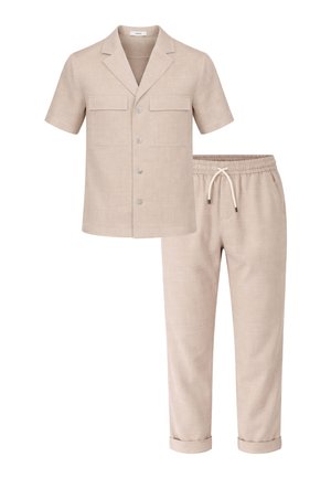Camicia beige a maniche corte con bottoni, due tasche sul petto e pantaloni abbinati con coulisse e risvolti sulle caviglie.