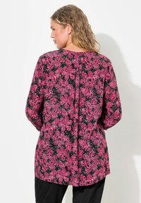 Langärmliges Oberteil mit schwarzem Hintergrund und pinkem Blumenmuster, Rundhalsausschnitt und geradem Schnitt. Strukturiertes Gewebe mit leichtem Fall.