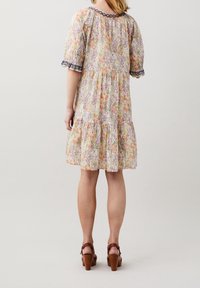 Robe fleurie avec des manches courtes bouffantes, dans des couleurs pastel, avec une taille fronc ée, une jupe à volants et une bordure en dentelle au niveau du col et des manches.