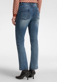 Jeans de denim de color azul claro con un corte recto, que cuentan con dos bolsillos traseros y un desvanecido sutil. Combinados con botines negros de tacón.