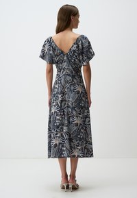 Bloemen midi-jurk in navy met pofmouwen en een diepe V-rug. Gemaakt van lichtgewicht stof met ingewikkelde bladeren- en bloemenpatronen.