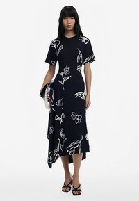 Granatowa sukienka z krótkimi rękawami i białymi, kwiatowymi wzorami, z nieregularnym dołem, wykonana z gładkiej, lekkiej tkaniny. Z dołączonymi akcesoriami.