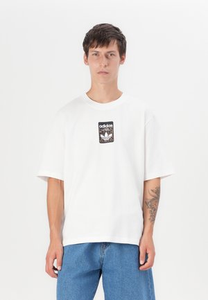 Hvit bomulls t-skjorte med korte ermer, med en svart og leopardmønstret Adidas-logo på brystet. Avslappet passform.
