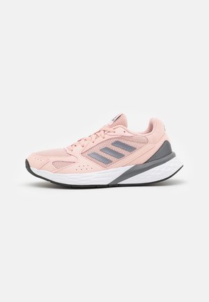 Chaussure de sport rose clair avec des bandes grises, semelle blanche amortissante et semelle extérieure noire, vue de côté sur un fond uni.