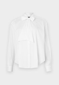 Blusa bianca con maniche lunghe, colletto a fiocco, chiusura frontale con bottoni e un fit morbido. Realizzata in tessuto liscio senza motivi o accenti.