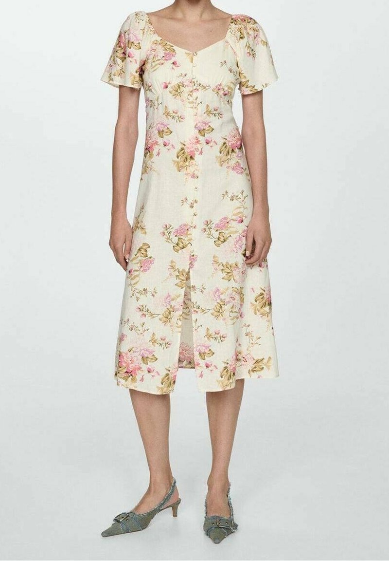 Robe florale en jaune clair avec des manches bouffantes courtes, bouton devant et longueur genou, ornée de motifs floraux roses et verts.