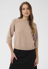 Világos rózsaszín, kötött pulóver háromnegyedes ujjakkal, bordázott nyakkivágással és szegéllyel. Finom csillogás található az egész anyagban.