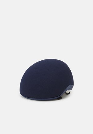 Casco de la Marina con una forma suave y redondeada. Cubierta de tela con pequeñas perforaciones en la parte superior. Presenta un lazo de sujeción en el lateral para asegurar.