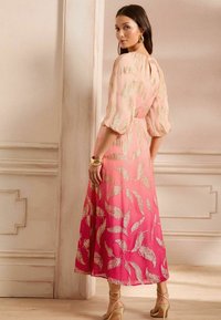 Vestido largo en ombré que transiciona de rosa claro a magenta, con patrones de hojas doradas, tejido texturizado y mangas abullonadas.