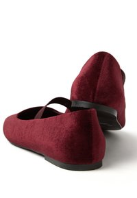 Pair of burgundy velvet ballet flats with black soles and a single strap across the top, shown from rear and side angles.