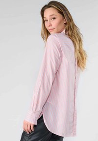 Light pink striped shirt with vertical lines in darker shades, long sleeves, button-up design, and a slightly curved hemline in the back.