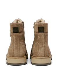 Bruine suède enkelboots met een zachte voering, een contrasterende rubberen zool en een achterste lipje. Zijkant met rits voor gemakkelijk aan- en uittrekken.