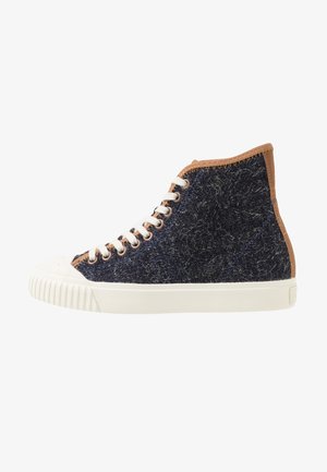 Sneaker alta con tessuto strutturato blu scuro, suola in gomma bianca e punta rinforzata, lacci bianchi e bordo marrone intorno alla caviglia e sul retro.