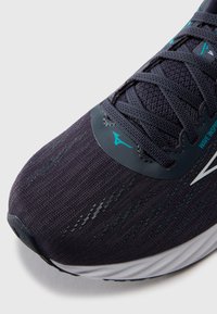 Dark navy running shoe with textured mesh upper, gray laces, turquoise accents, and white midsole. Features curved toe and logo on the side.