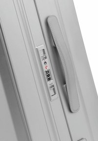 Valise grise avec surface texturée, serrure à combinaison, approuvée par la TSA, poignée intégrée et crochet latéral pour un voyage en toute sécurité.