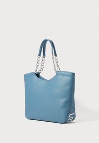 Bolsa tote de couro azul com correntes duplas e alças de couro, bordas superiores ligeiramente arredondadas e letras "LO" parciais no canto inferior.