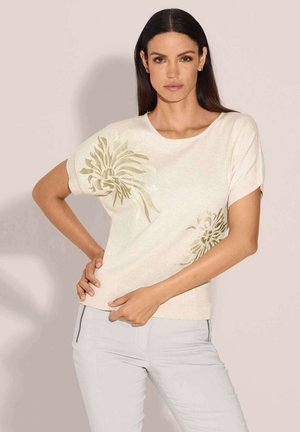 Hellbeige Kurzarm-Pullover mit grünem Blattmuster. Weicher Stoff, runder Ausschnitt, tailliert, glatte Stoffoberfläche.