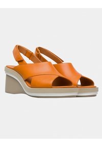 Oranje leren wedge sandalen met open tenen, voorzien van kruislings straps en een verstelbare achterband, op een neutraal gekleurde platte zool.