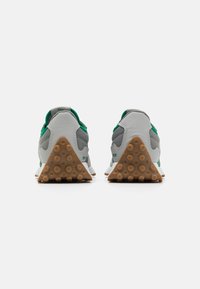 Zapatillas grises con una superficie texturizada, acentos verdes y una suela de goma triangular con puntos de tracción circulares. Diseño minimalista.