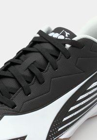 Black athletic shoe featuring a textured upper, white accents, and pronounced zigzag design, with black laces and a cushioned collar.