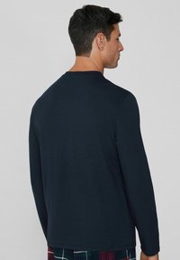 Námořnické tričko s dlouhým rukávem, kulatým výstřihem, hladkým materiálem a pohodlným střihem. Zobrazeno ze zadního úhlu, se zdůrazněním švu na rameni a prošívání.