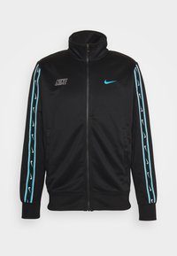 Svart zip-up jacka med hög krage, med blåa accentremsor och Nike-logotyper på bröstet och ärmarna. Tillverkad av slätt tyg.