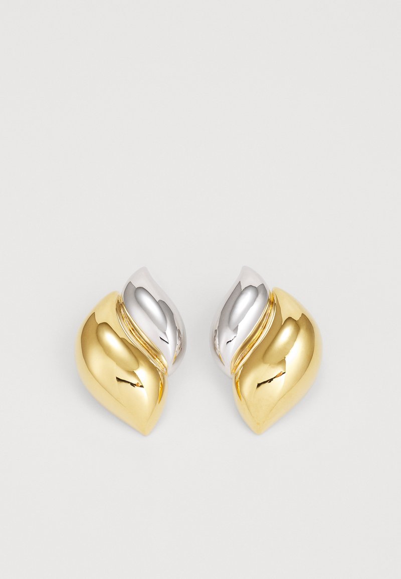 Zlaté a strieborné kovové náušnice s zaobleným, zakriveným tvarom, ktoré majú dizajn pripomínajúci vlny a leštenú textúru.