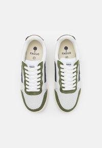 Scarpe da ginnastica bianche con accenti in suede verde e strisce nere sui lati. Texture perforata sulla punta, con lacci bianchi e un tab di gomma marrone sul tallone.