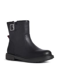 Botín negro de cuero con un detalle de hebilla lateral, puntera redonda, parte superior texturizada, tacón bajo de goma y acento rojo en la parte trasera.
