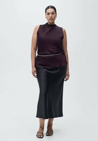 Top bez rukávů s vysokým límcem v burgundské barvě, kombinovaný s elegantní dlouhou černou saténovou sukní. Obsahuje stříbrný řetízek jako pásek a černé sandály na řemínky.