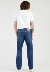 Denim jeans in een donkere blauwe was met een rechte pijp, voorzien van een bruine leren achterpatch en dubbele achterzakken met stikseldetails.