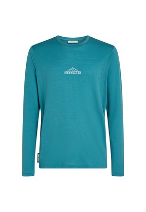 Tealfärgad långärmad crewneck-tröja med vitt "ICEBREAKER"-text och bergslogo på bröstet, samt en liten sidetikett.