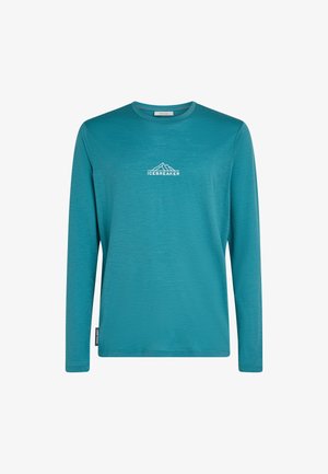 Teal langemouwen crewneck shirt met witte "ICEBREAKER" tekst en berglogo op de borst, en een klein zijlabel.