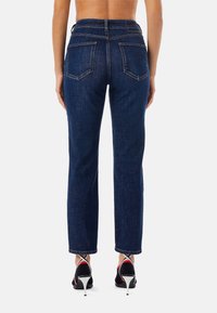 Mörkblå denimjeans med rak benmodell. Har två bakfickor och en något fransande fåll. Kommer med svarta och röda klackar.