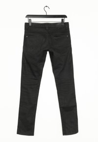 Jeans de mezclilla negra con un corte ajustado, que presentan un diseño de cinco bolsillos y un ligero desvanecimiento en las piernas. A la venta colgados de un gancho negro.