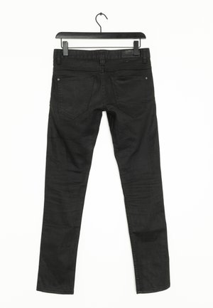 Jean en denim noir avec une coupe slim, présentant un design à cinq poches et un léger dégradé sur les jambes. Pend d'un crochet noir.