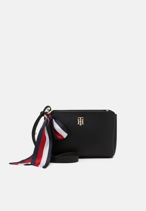 Black leather crossbody bag with gold logo and attached navy, white, and red striped scarf tied to strap.