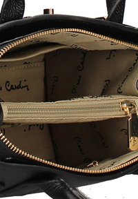 Borsa nera con zip dorata aperta che rivela l'interno beige stampato con il testo ripetuto in nero "Pierre Cardin".