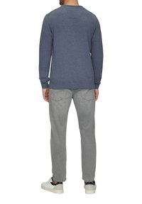 Pelēks kokvilnas sporta krekls ar garām piedurknēm, apaļo kakla izgriezumu un ribotām aprocēm, apvienots ar gaiši pelēkiem džinsiem un baltām kedām.