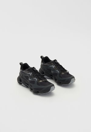 Μαύρα αθλητικά παπούτσια με πλέγμα υφής στο πάνω μέρος, διαθέτουν χοντρή σόλα, κλείσιμο με κορδόνια και διακριτικές γκρίζες λεπτομέρειες.