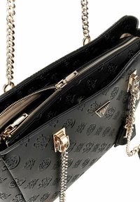 Sac à main noir avec un motif en relief, doté d'une chaîne en métal doré et d'une fermeture éclair, mettant en avant une texture lisse et un design structuré.