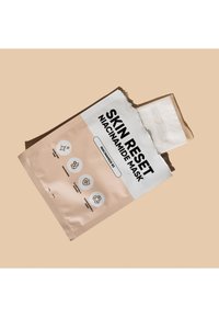 Verpackung einer Niacinamid-Gesichtsmaske mit weichem rosa Hintergrund, fettem schwarzem Text und Symbolen für die Vorteile. Die Verpackung hat einen eingerissenen Rand, der eine Maske enthüllt.