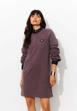 Robe sweat violette avec des manches longues, un col côtelé et un petit logo brodé sur la poitrine. Accent de poignet en métal.