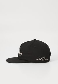 Black baseball cap made of cotton with a curved visor. Features white embroidered text on the front and side. Classic design.