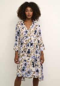 Robe florale en beige, bleu clair et noir. Dotée d'un décolleté en V, de manches trois-quarts et d'un design fluide à étages avec un tissu texturé.