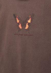 T-shirt in cotone marrone con una grafica di farfalla in rosso e nero, con il testo "NATUR SERVICE - LOS ANGELES" sotto il design.