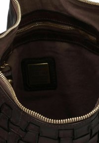 Interno di una borsa tote in pelle color marrone scuro con una texture intrecciata, chiusura con zipper dorato e una fodera liscia; presenta un'etichetta piccola all'interno.