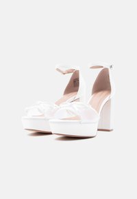 Άσπλα πλατφόρμα πέδιλα με χοντρό τακούνι, λουράκι στον αστράγαλο και μπροστινό σχέδιο σταυρωτό με λεία υφή.